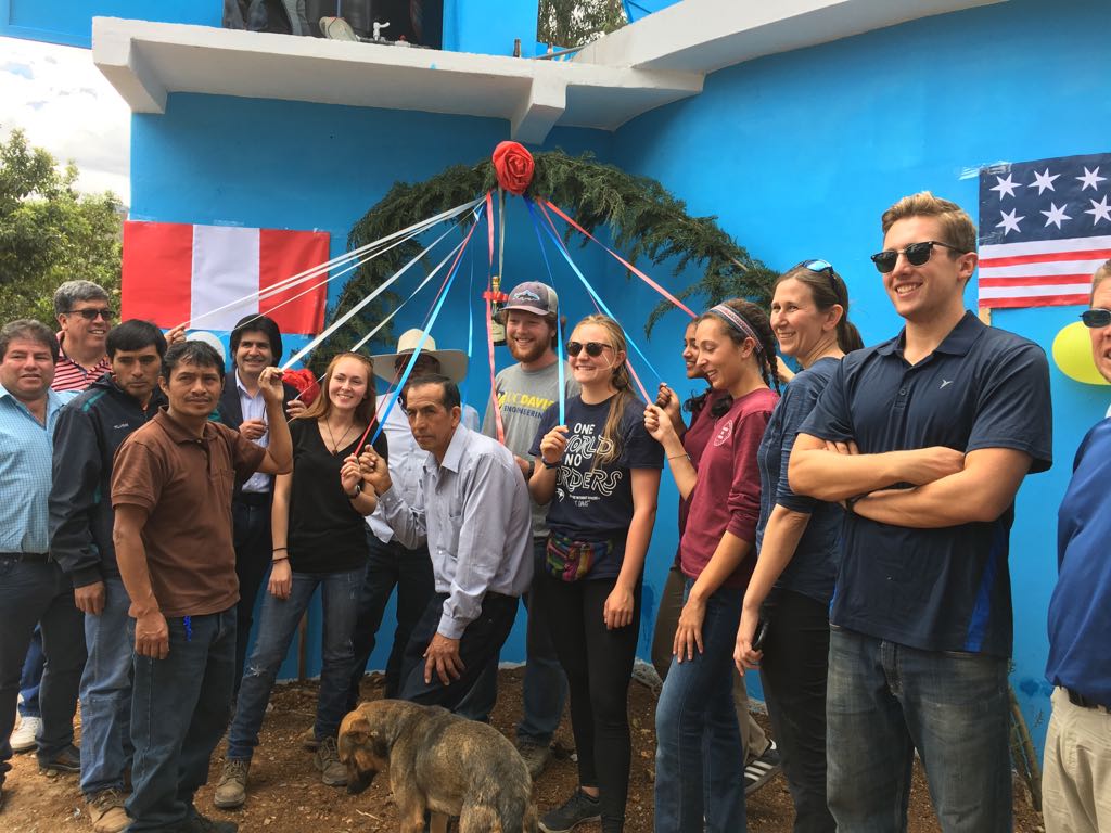 Nicolas Dante Dilliot posing with a group of people in front of blue wall