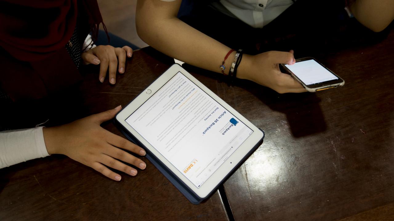 People handling a tablet and phone
