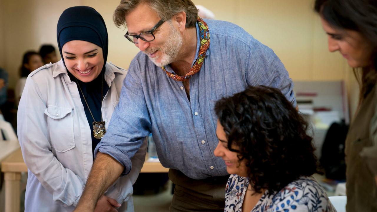 Keith David Watenpaugh shares his Backpack with Hoda al-Rifai, director of the Ruwad al-Tanmeya Center in Tripoli, Lebanon and two other people, all looking down at something below them.
