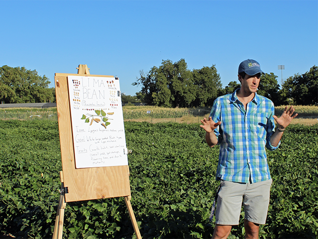 Person standing in field with presentation board