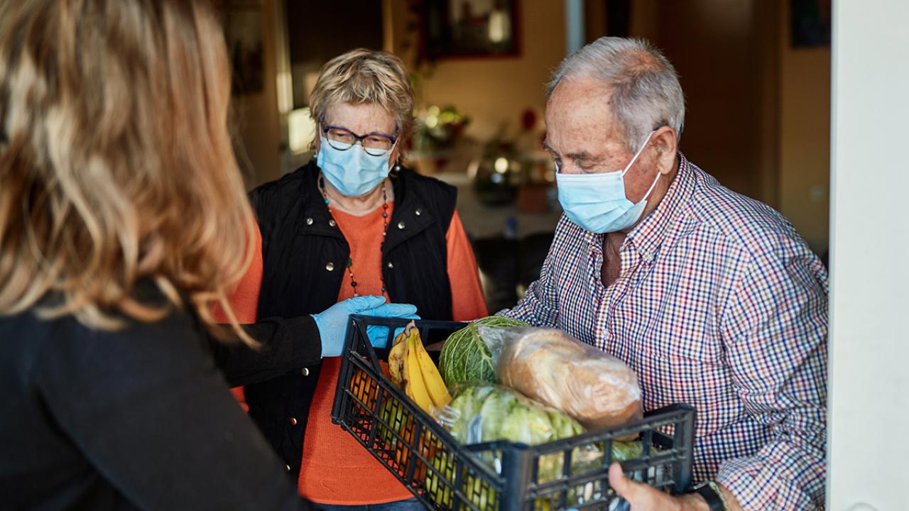 Two people receiving basket of food from another person