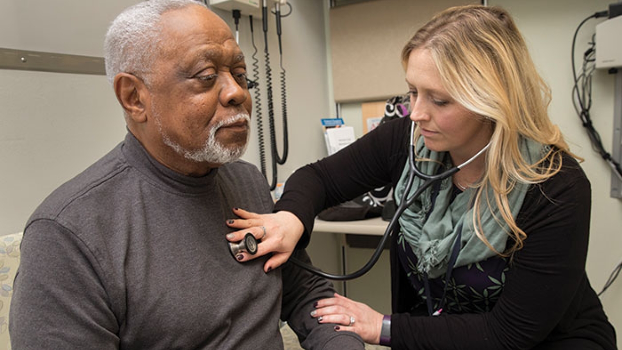 Person placing stethoscope on someone's chest in an exam room