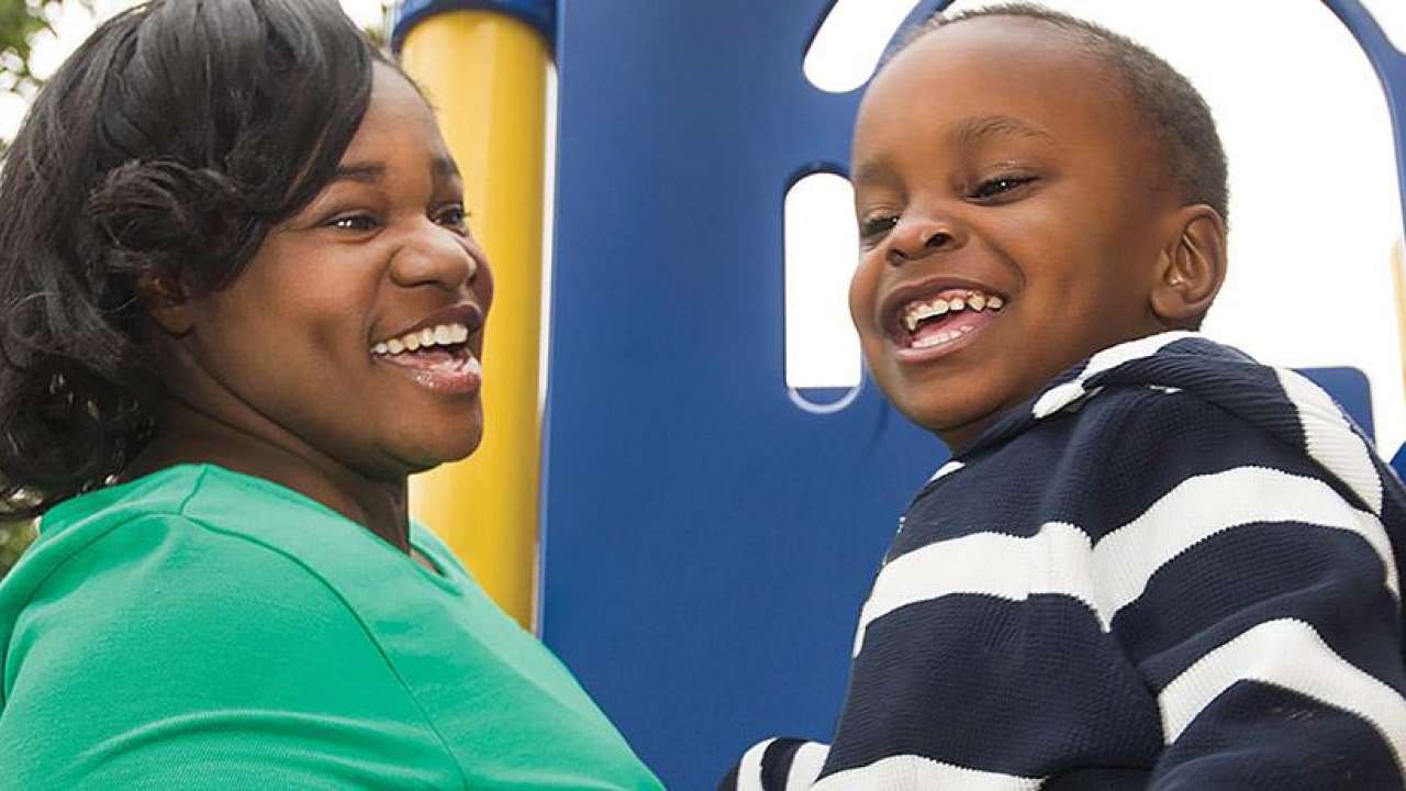 Young mother and son smiling at a playground.