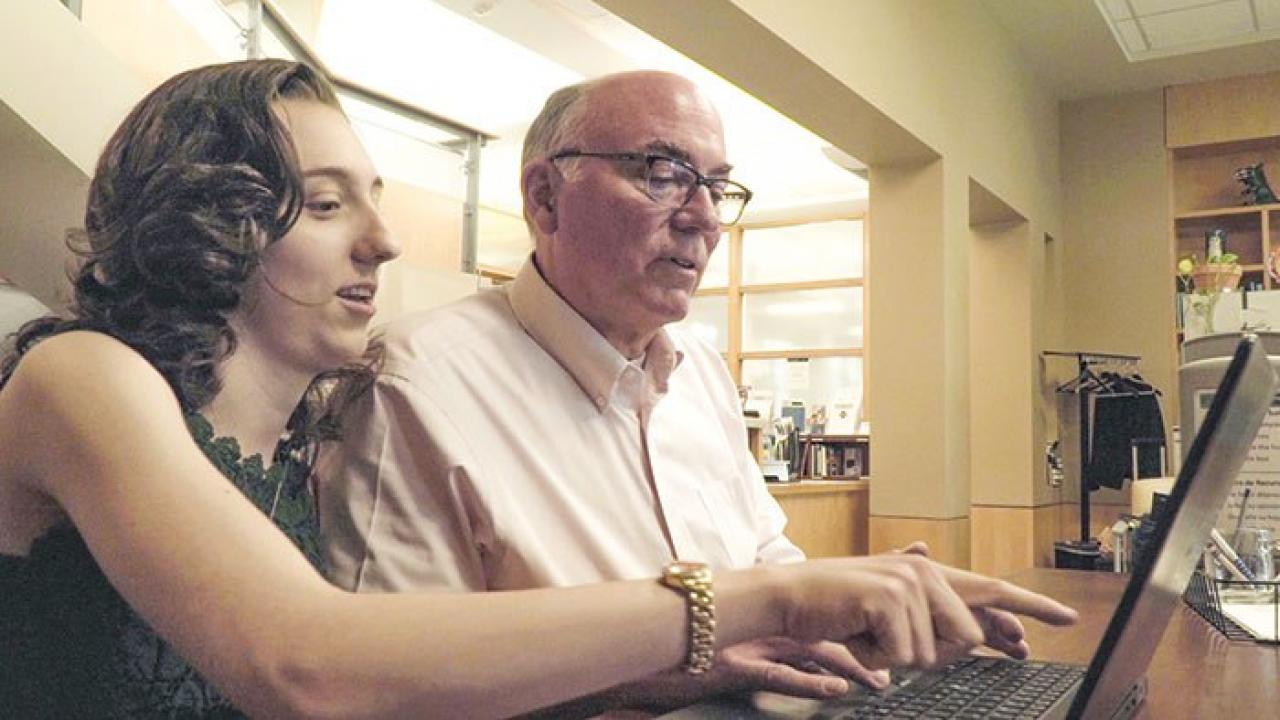 Father and daughter sitting in front of a laptop.