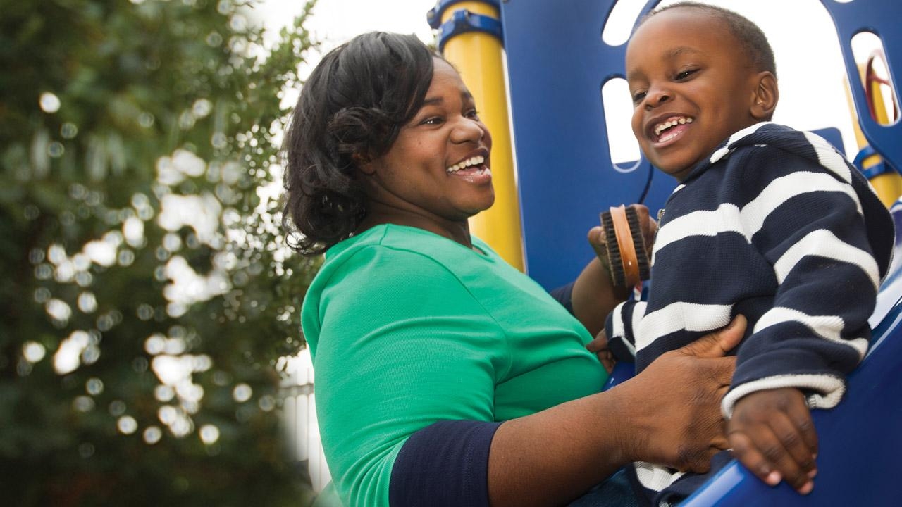 Young mother and son smiling at a playground.