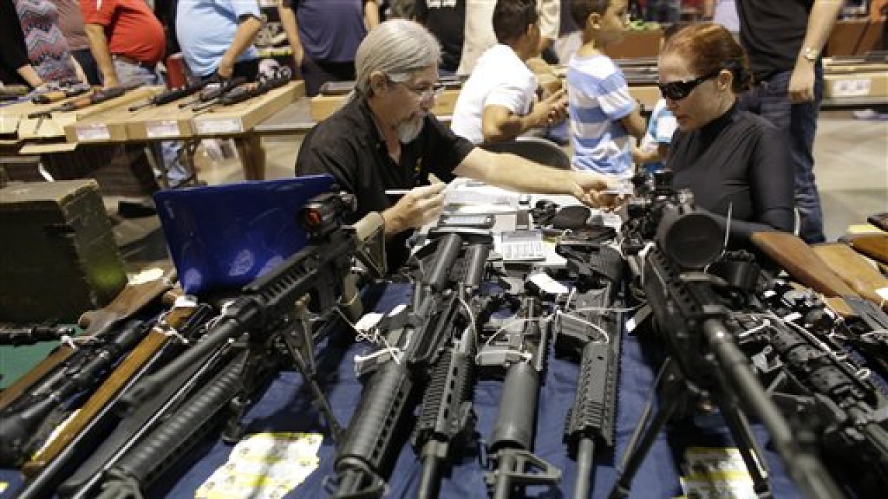 Harvey Kornnfield, owner of Airport Pawn, left, works on a sale with Bamula Schlesinger, right, at a gun show hosted by Florida Gun Shows, Saturday, Jan. 9, 2016, in Miami. Schlesinger purchased an Uzi and a Smith & Wesson 38. (AP) Harvey Kornnfield