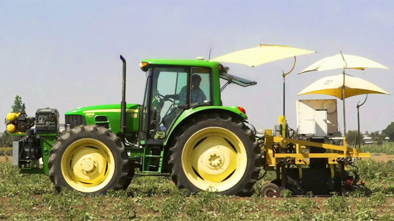 Tractor pulling a futuristic looking robot plant harvester