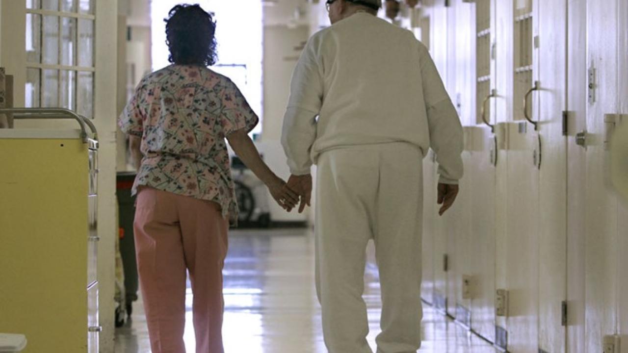 Elderly Latino couple walking down a hospital hallway