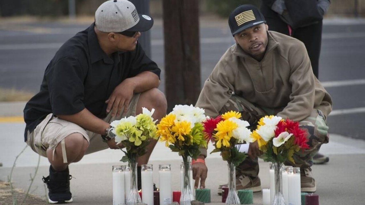 Steven Stanford, left, and Damon Flenaugh kneel by flowers in memorium of Flenaugh’s brother, Dazion, a mentally ill man shot last year by Sacramento police / Randy Pench Two men at a memorial with flowers