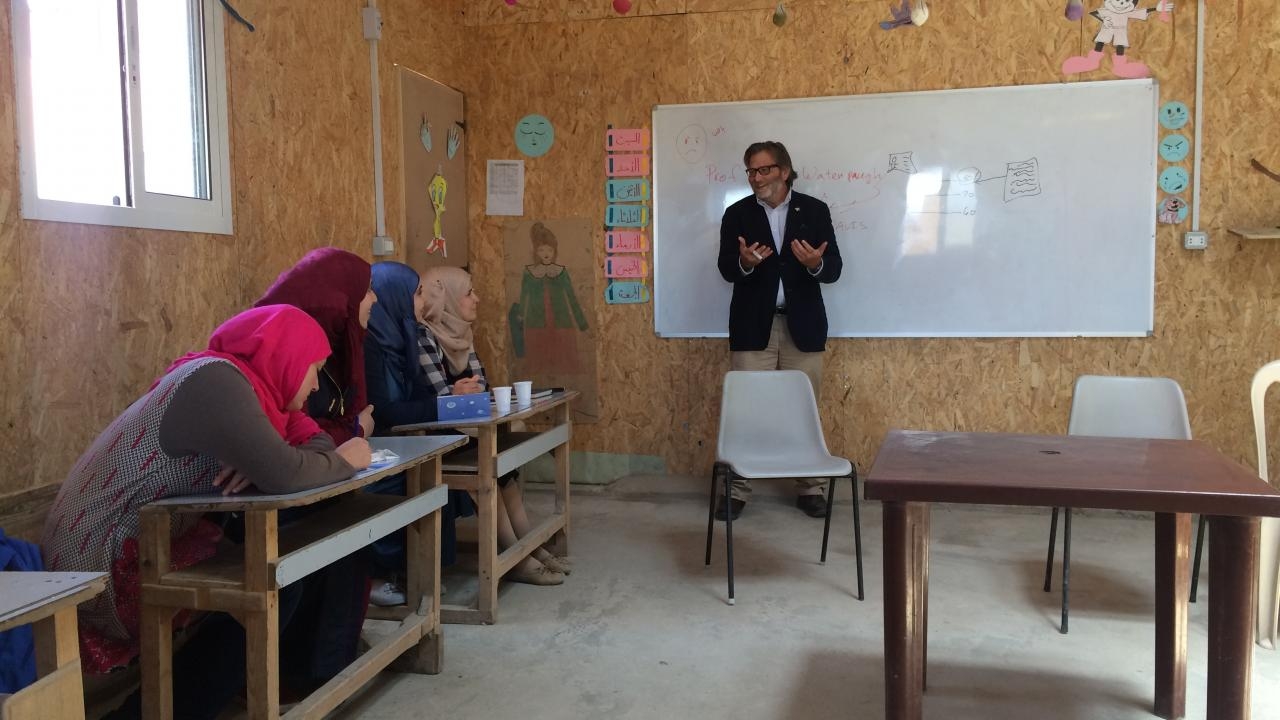 David Keith Watenpaugh discussing the Article 26 Backpack™ with Syrian refugees in Lebanon, May 2017. Man teaching at the white board and Syrian refugee students at desks.