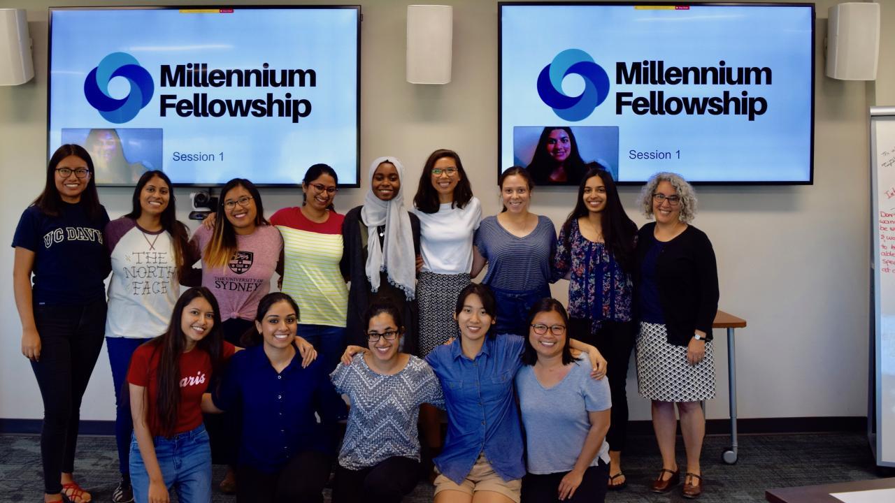Group of students in front of TV screens that say Millennium Fellowship. 