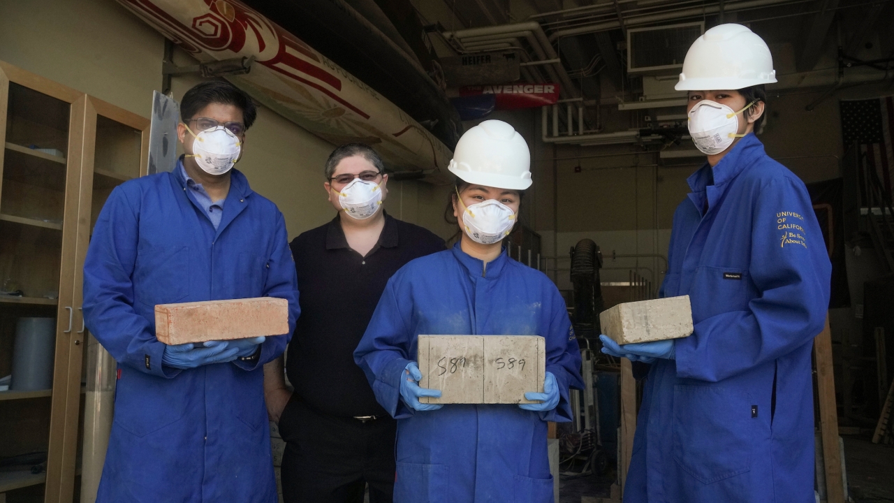 Four people posing for camera, three of the four holding blocks.