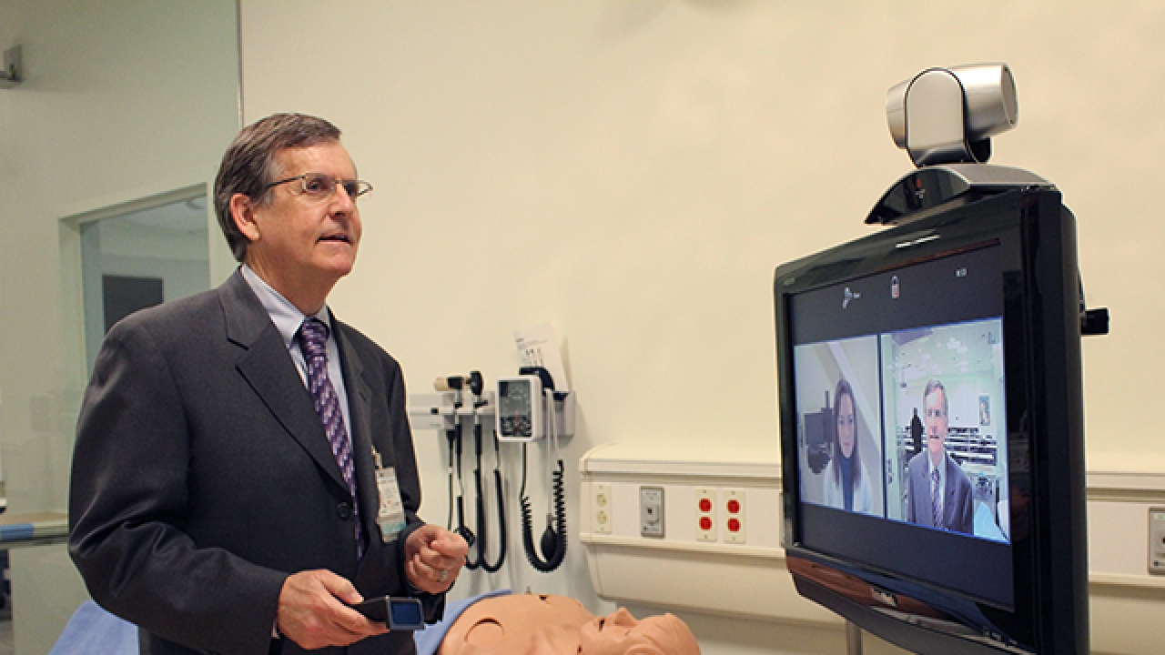 Tom Nesbitt appearing to speak with someone via a computer screen in a health care setting.
