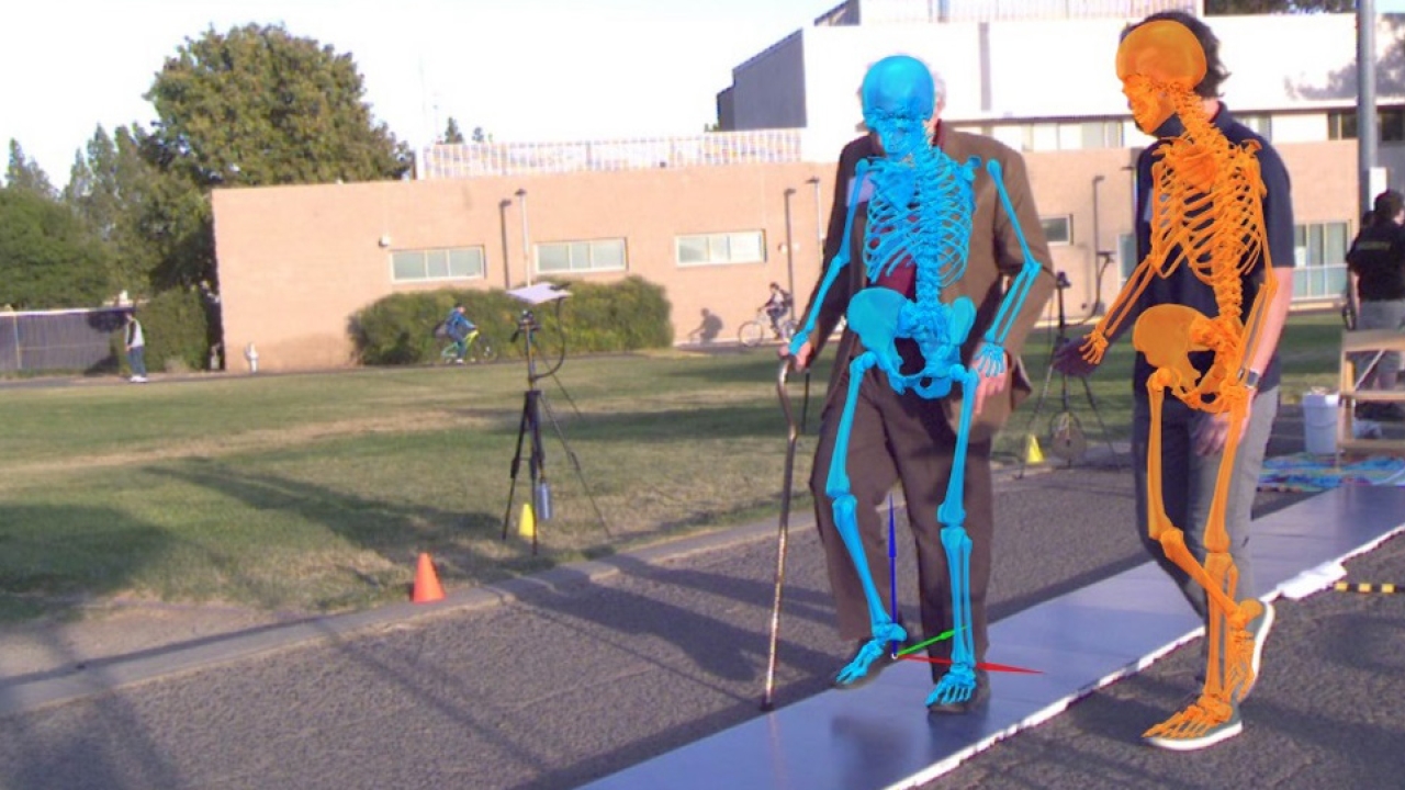 Two people doing a trial outside with sensors set up and a blue and orange skeletons obscuring the subjects.