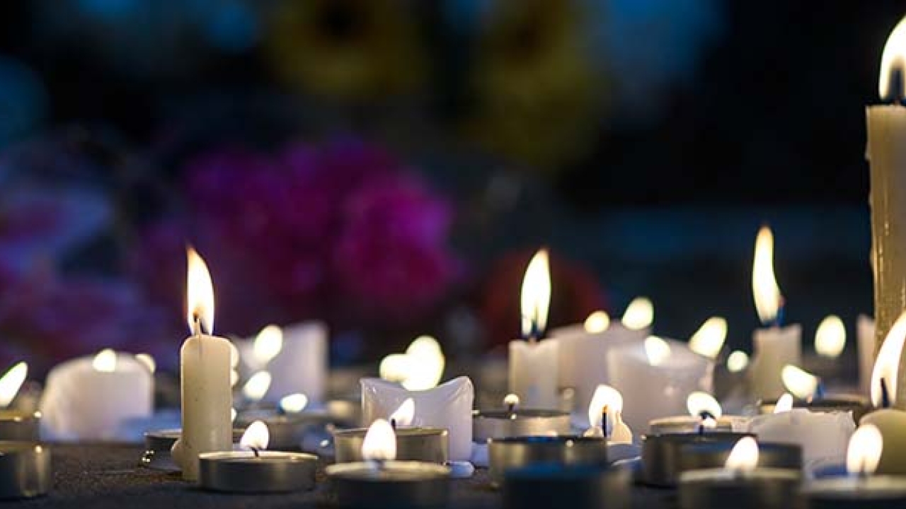 Multiple tea light and taper candles grouped together burning.