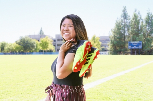Tami Kwong posing with cleats over her shoulder