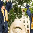 Two UC Davis graduating students jumping in front of an egghead