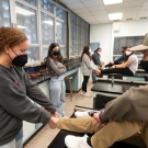 Student conducting an ankle examination by touching another students ankle to inspect.