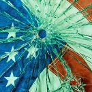 American flag behind a sheet of glass shattered from a bullet hole