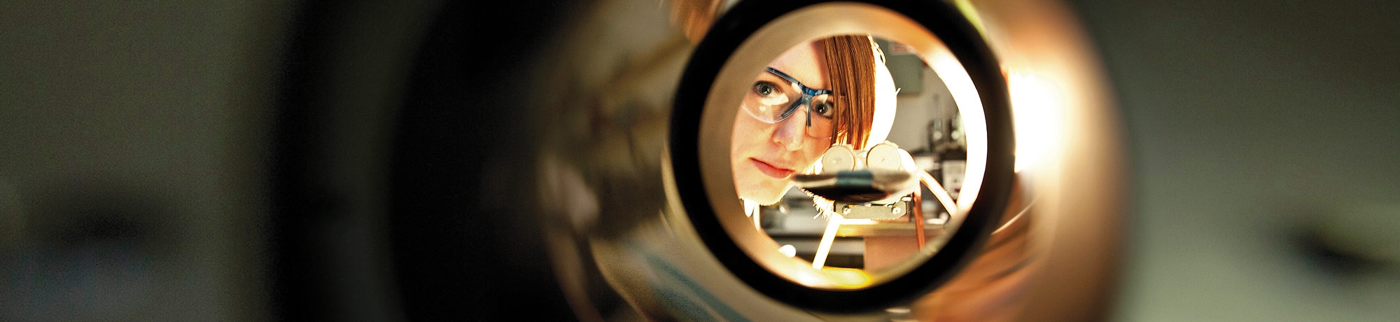Medical scientist looking through a circular piece of equipment. 